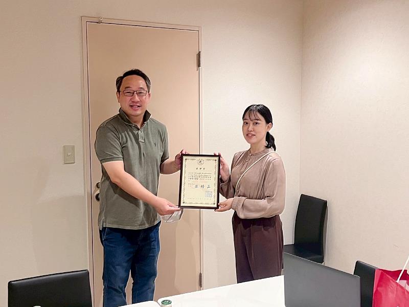 南華大學傳播系學生至日本宮崎TMJ公司實習,計畫主持人暨傳播系副主任兼系務執行長黃彥穎(左)代表學校致贈感謝狀予TMJ公司,由擔當主任篠原裕菜(右)代表受贈。