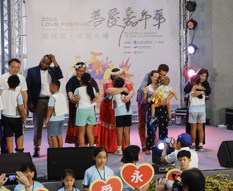 駐台單位代表上台與小朋友擁抱(右起為馬尼拉經濟文化辦事處代表、瑞士商務辦事處副處長及家人、馬紹爾群島共和國大使館大使、吐瓦魯國大使館大使、聖克里斯多福及尼維斯大使館大使)。(貿協提供)