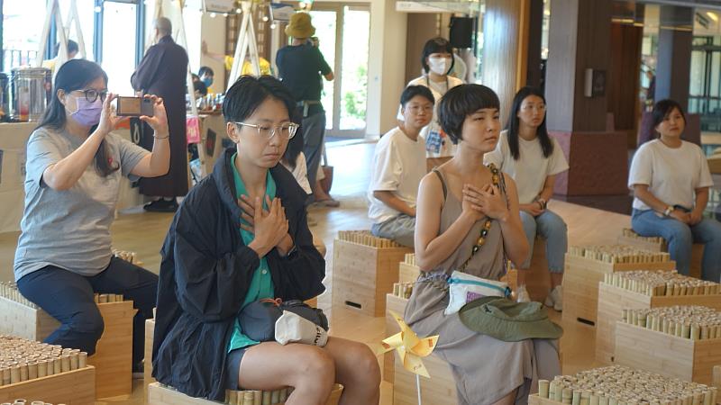 參與者雙手輕放胸前，神情專注地坐在竹製座椅上，於活動中進行靜心體驗。（圖由靈鷲山福城提供）