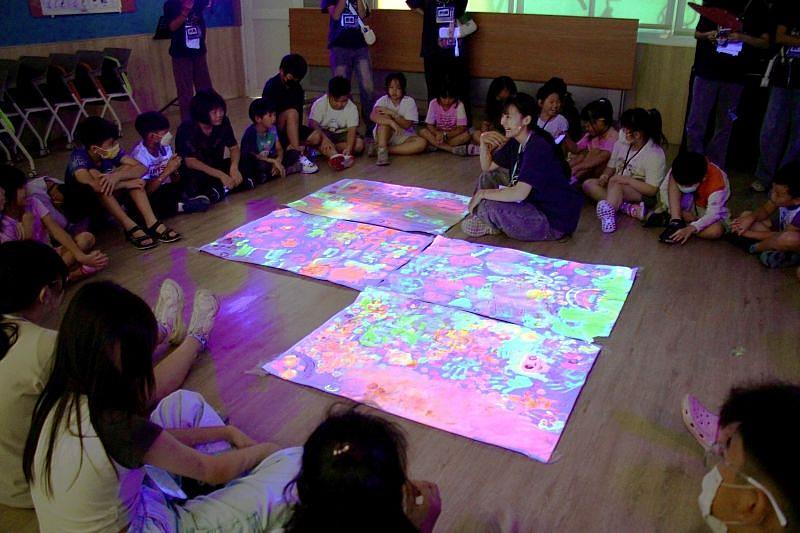 南臺科大幼保系「童年的小時光」營隊運用螢光顏料和燈光效果與小學生共同創作發光發熱。