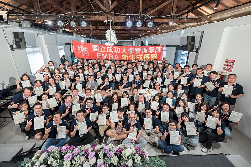成大EMBA新生營學員持結業證書與成大師長合影。圖中鄰桌而座者左2至左5為：謝中奇導師、管院蘇佩芳院長、蔡佳良執行長、張巍勳導師