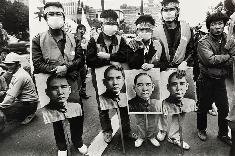 〈還我客家語遊行〉1988年，立法院前。本作品為1988年客家族群發起還我客語運動遊行，遊行隊伍行至立法院前，要求立法還予客家族群權益。畫面中客家族群帶著孫文肖像，強調國父亦為客家人，應尊重國父的母語文化。