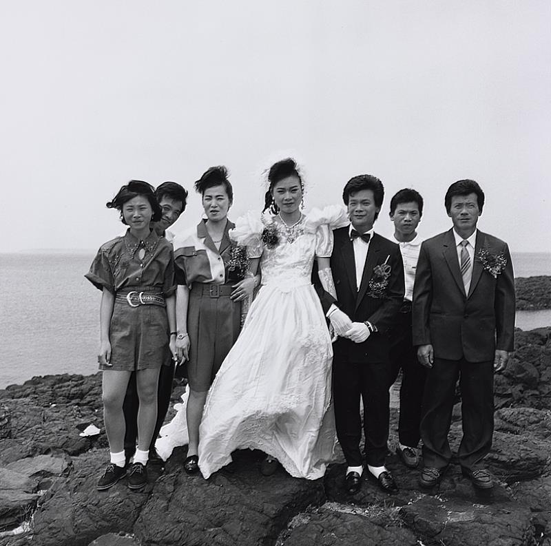 《澎湖印記》07︰〈風櫃〉1991年，馬公風櫃。_本作品是攝影家謝三泰外甥結婚當日所拍攝。男方就住在澎湖風櫃洞前，當日迎娶拜堂後，謝三泰為跳脫傳統在門庭前合影的喜事照片，決定請男方家人到風櫃洞旁的玄武岩石岸拍攝一張全家合影。