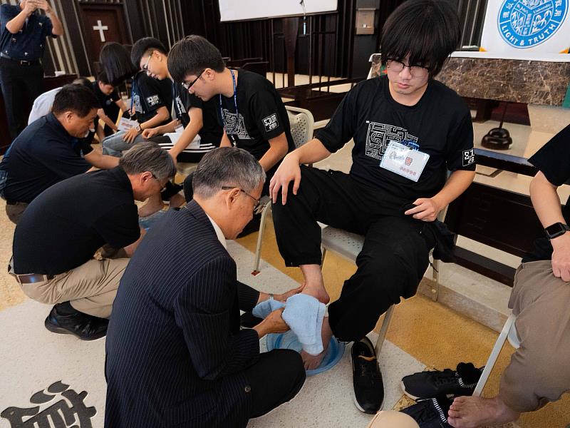 唐彥博校長於濯足禮中，俯身為學生會會長秦仕晉洗腳，傳遞謙卑服務精神。