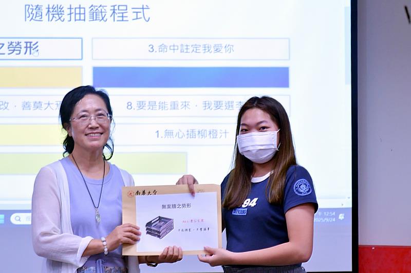 南華大學文學系感謝師恩，以創意逗趣表心意，李艷梅副教授（左）獲學生頒贈「慈悲系女神獎」，並獲得「無案牘之勞形」獎品。