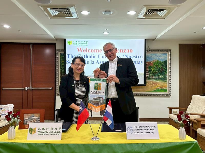 莊慧玲校長(左)於簽約儀式後,致贈校錦旗予巴拉圭天主教大學校長,象徵雙方情誼與合作再深化。