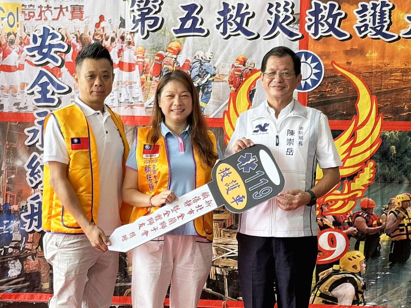 顧蓓靜賢伉儷（左）以鑰匙模型代表捐贈消防局救護車給予消防局長陳崇岳