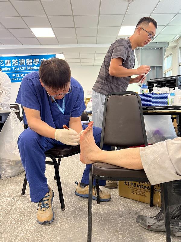 花蓮慈院一般外科主任陳言丞(左)與骨科陳林睦醫師為傷患縫補腳上的傷口。