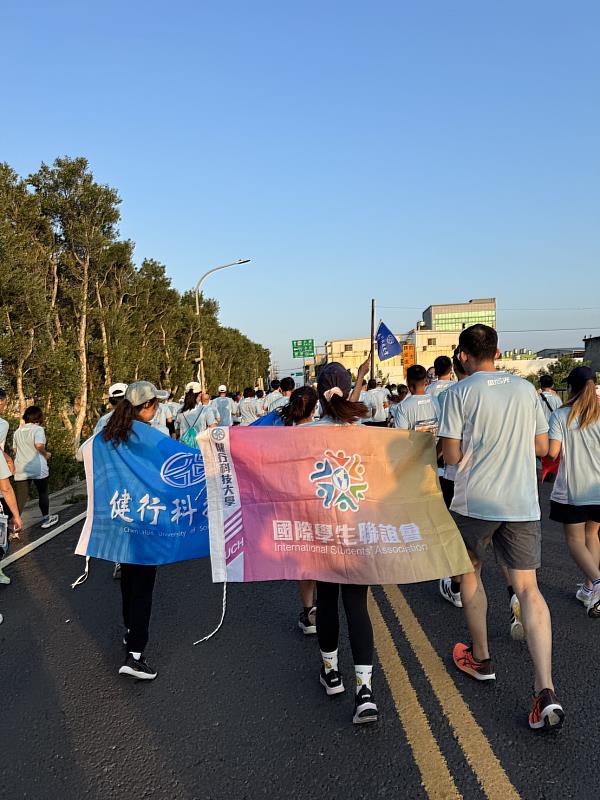 圖2／跑在晨光裡 校旗與國際學生聯誼會旗幟在賽道上飄揚，隊形整齊。