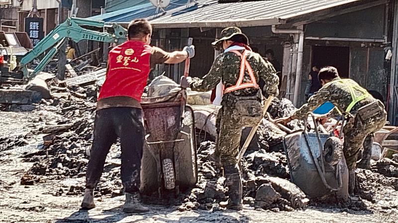 1、靈鷲山志工在泥濘中搬運物資、協助清理家園。（靈鷲山佛教教團提供）