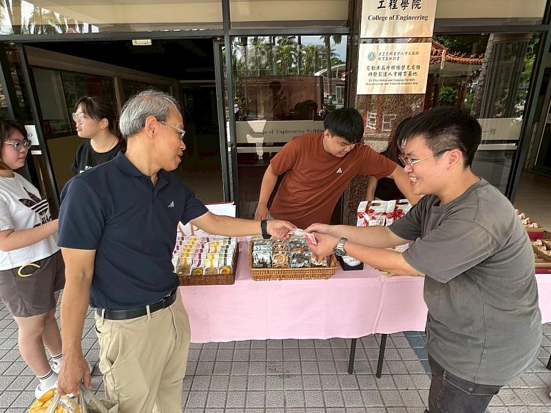 畢製團隊「暖暖堡」成員陳柏翰（右）向師長遞送商家名片