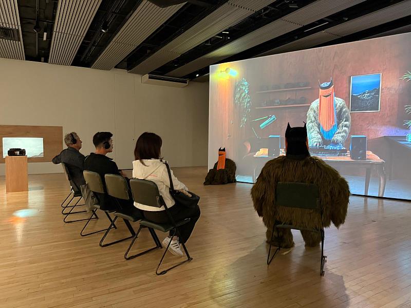 臺灣藝術家李奧森個展《孤獨感的存在》現場觀眾帶上耳機聆聽作品音樂及觀賞影像（駐英代表處文化組提供）