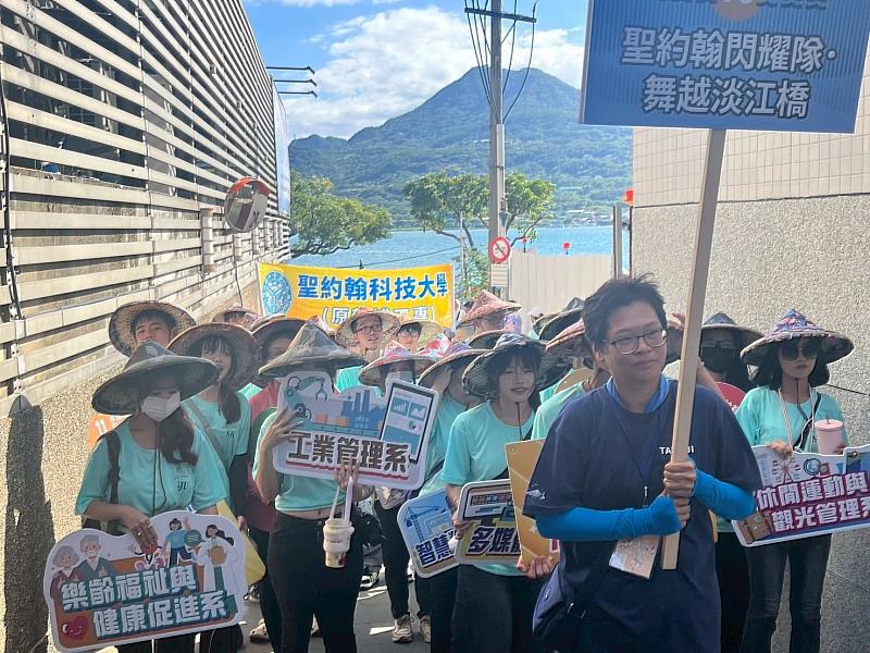 聖約翰師生以淡江大橋為意象,自河畔整隊出發,象徵校園專業與地方文化的緊密連結。
