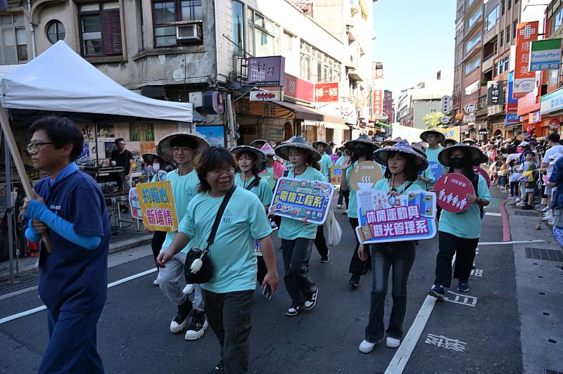 聖約翰科大師生走進淡水老街踩街隊伍,舉牌展現青春風采,熱情融入社區慶典。