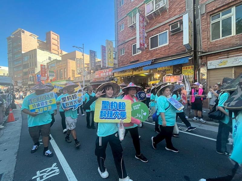 在淡水老街熱鬧踩街中,聖約翰科大隊伍展現青春活力,吸引沿途民眾拍照喝采。