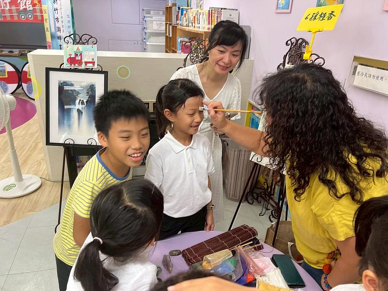 孫桂香藝術家於學童額頭示範膠彩畫