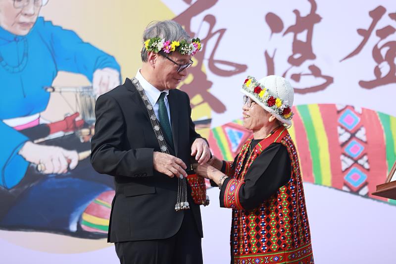 新科人間國寶Sunay Paelabang孫菊花（右）回贈親手製作的「攜物袋」予文化部長李遠，為其掛上並悉心調整。
