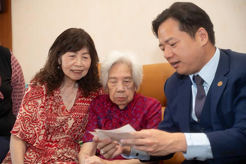 代理市長邱臣遠與羅奶奶一同觀賞照片，回憶過往。