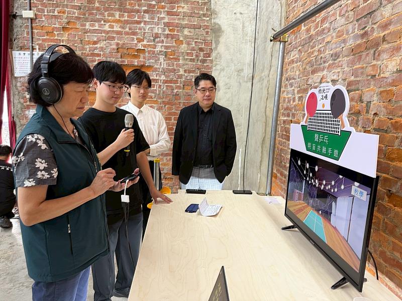 臺南市政府社會局局長郭乃文親臨《微光之境》特展現場，十分投入體驗南臺科大多樂系師生團隊開發的手機遊戲《聲乒乓》。