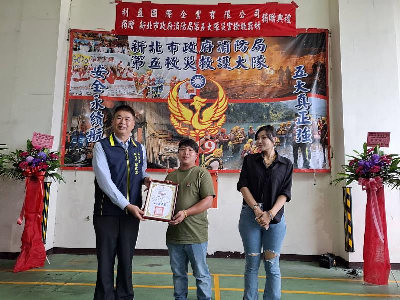 照片:消防局副局長蔡武忠回贈感謝狀給予董事長王靖元與夫人廖韋萲。