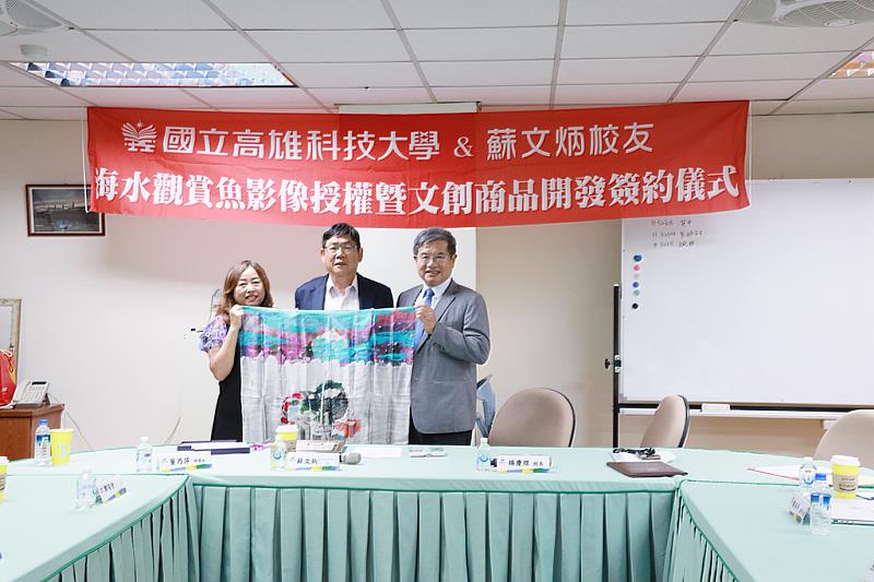 國立高雄科技大學傑出校友分散世界各地,現任僑務委員蘇文炳(圖中)在印尼打造觀賞魚王國Bali Aquarich,掌握全球海水觀賞魚輸出龍頭地位,利用返台機會,日前造訪母校楠梓校區,並且捐贈其擁有之觀賞魚種影像授權10年,做相關研究、周邊開發使用,並且將收益捐作獎助學金。高科大校長楊慶煜(圖右)以青藝獎典藏藝術品開發之文創絲巾回贈蘇文炳之夫人董乃萍(圖左),展示高科大開發精緻化文創周邊之成功範例。