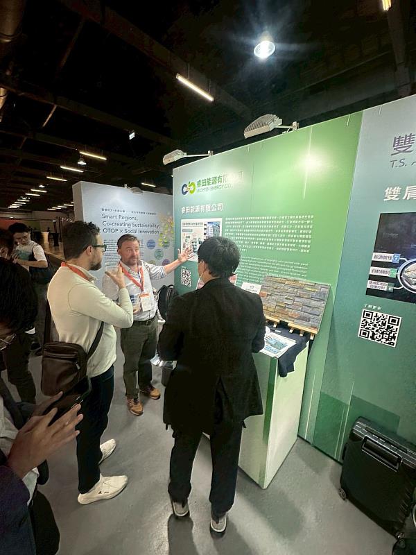 睿田許恩召產品總監（右）向歐洲企業代表說明可循環彩繪光電模組如何結合建築立面應用，達成兼具美學與創能的永續解決方案，現場獲得高度興趣與技術交流。