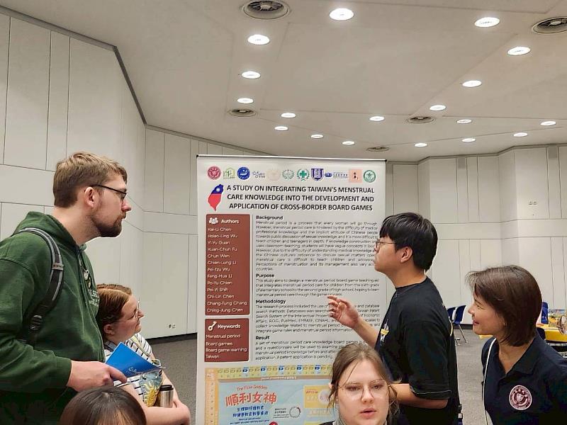 長榮大學護理系學生傅冠鈞向詢問的國際友人熱情介紹「順利女神生理期照護」桌遊之設計