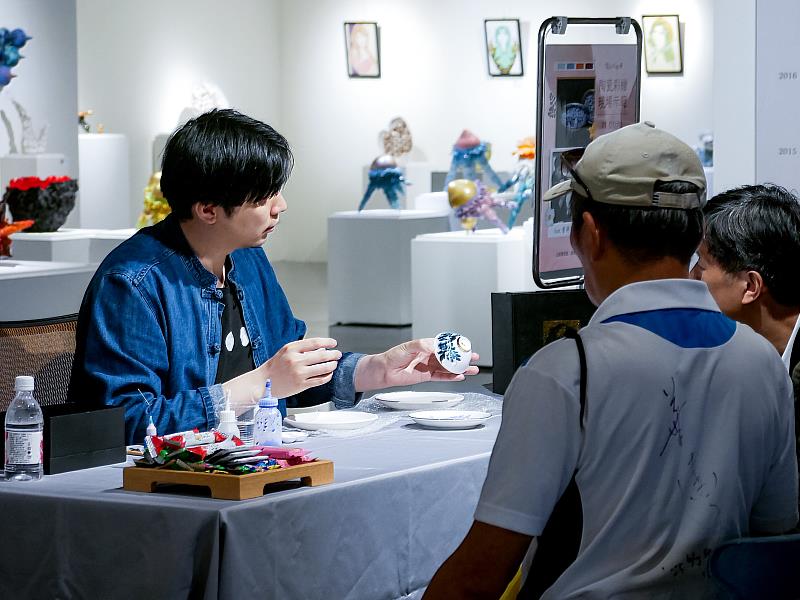 藝術家曾祥軒於示範前與藏家及觀眾交流,分享陶瓷彩繪的材料與創作理念,現場氣氛熱絡。