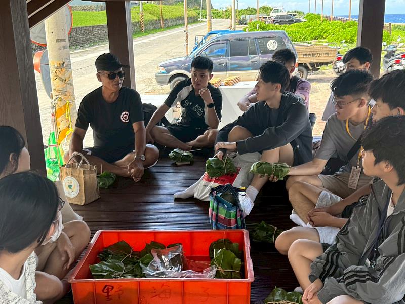 南臺科大學生體驗蘭嶼雅美族傳統美食。圖中學生們專注聆聽當地住民(左上)解說每一項食材背後的意義與傳統文化,促進跨文化理解與尊重。