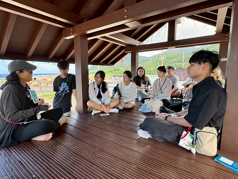 部落解說員(左一)向南臺科大學生們說明雅美族文化的深度演化,內容涵蓋族語、生死觀、植物應用、建築、材料與節慶等面向,藉此增進學生對在地文化的認同與尊重。