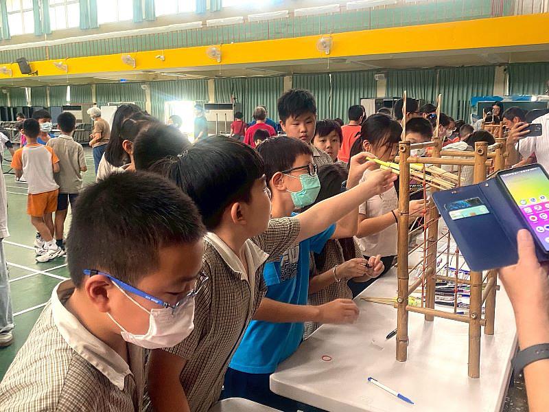 竹運會現場。學童們闖關完畢後，寫上祈福語，將竹製祈福棒放入竹炮架的情景。此儀式結合蜂炮民俗，讓學童在活動的尾聲，也獲得傳統文化的祝福。