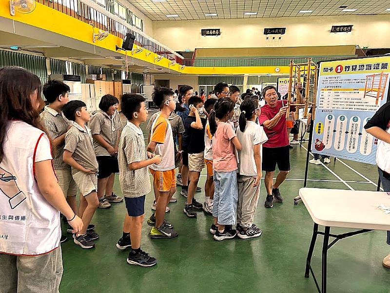 竹運會第一關「竹見認識炮架」。圖為南臺科大館員學生擔任的關主正用小型竹砲臺，向學童講解最早的砲架如何以竹子製成，為學童扎根在地民俗文化知識。