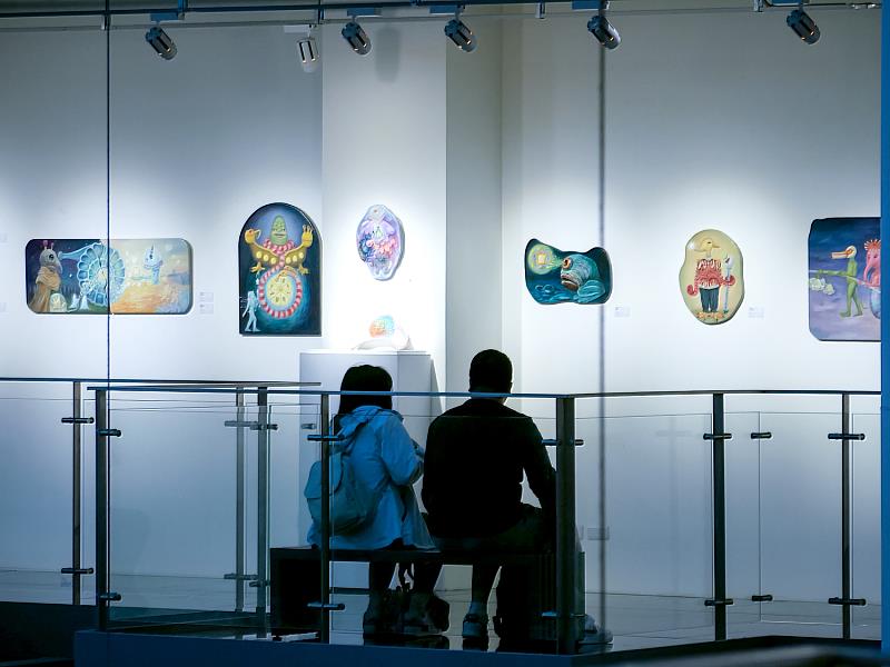 觀眾並肩坐在展場角落，安靜地凝視作品，在柔和的光影與色彩中，彷彿聽見內心的呼吸，感受藝術帶來的療癒力量。