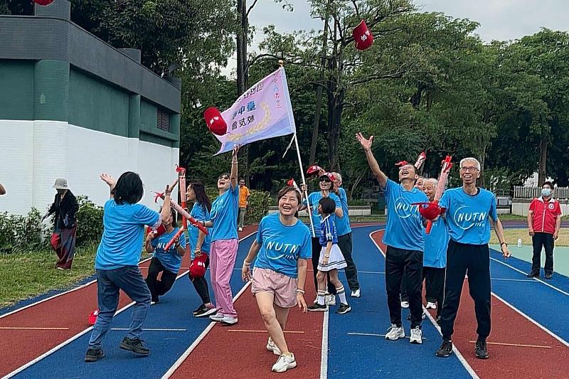 南大臺中校友熱情滿滿，揮舞紅帽歡呼迎火，現場氣氛熱力四射。