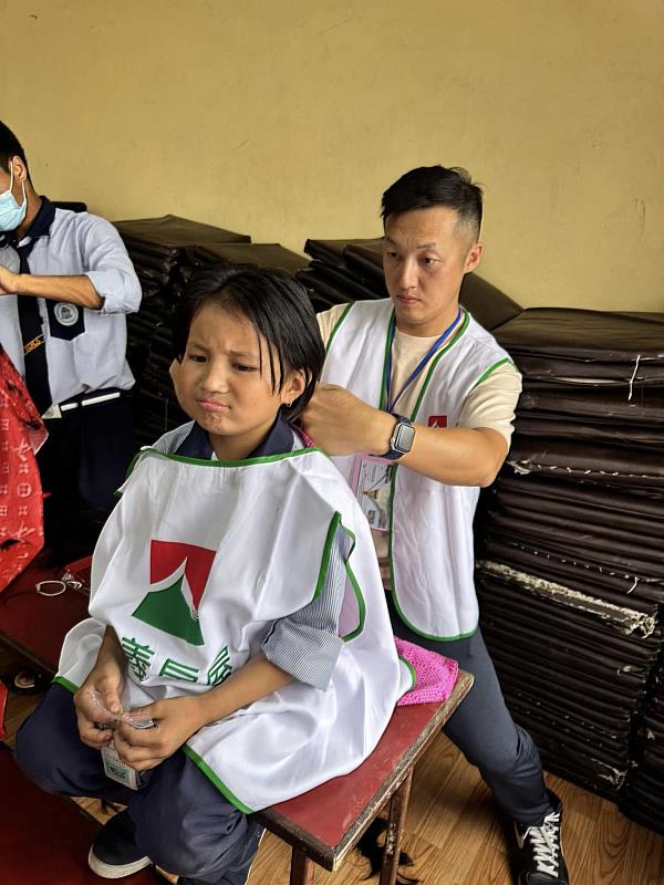 滿頭蟲卵的尼泊爾女孩,因被醫生團評估頭髮需剪短才能免除頭蝨困擾面露不捨,信義房屋吳正義在當地協助孩子修髮