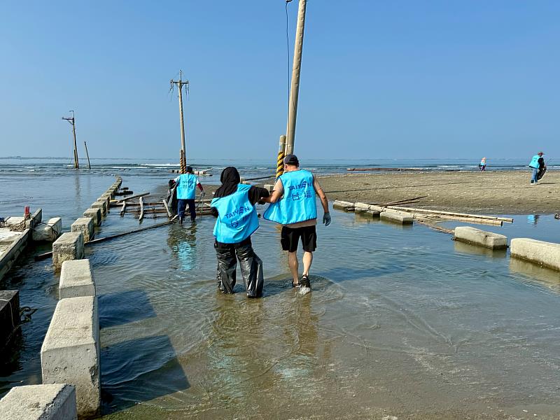 臺鹽生技妝品廠志工們不畏潮水未退的積水環境，穿著雨鞋、腳綁垃圾袋涉水而行，艱辛完成淨灘任務。