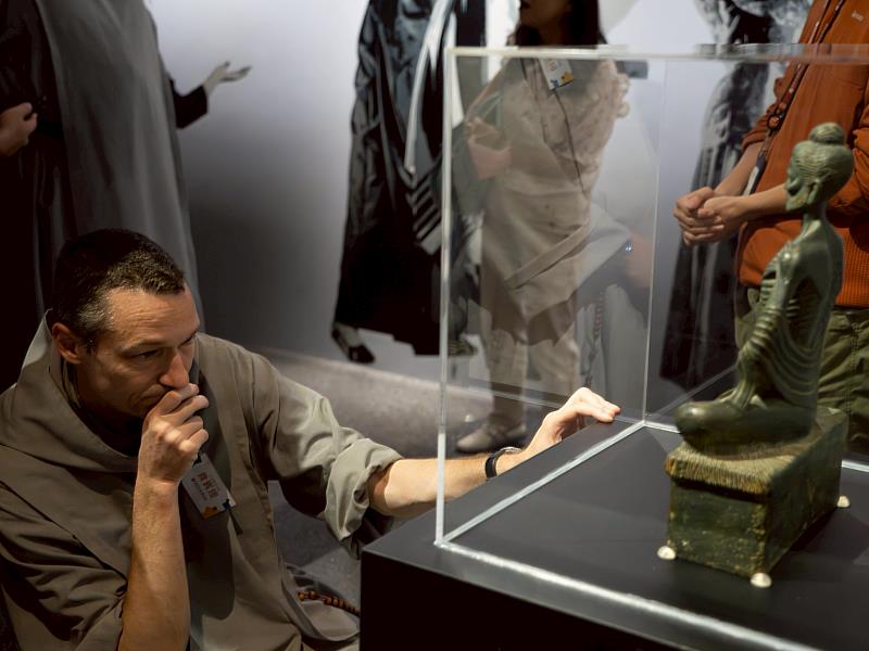 神父仔細研究釋迦牟尼苦行像。（圖由世界宗教博物館提供）