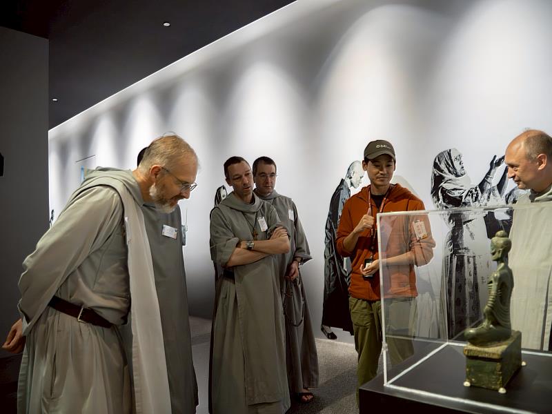 天主教神父在在世界宗教博物館典藏研究組組長陳昱瑋導覽下，參觀《文物開窗系列特展：成為你自己的光》。（圖由世界宗教博物館提供）