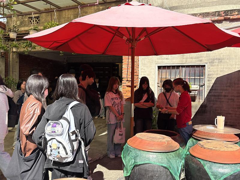南華大學學生至「丸莊醬油」參訪,學生們品嚐發酵缸中的醬油,味道更濃郁甘醇。
