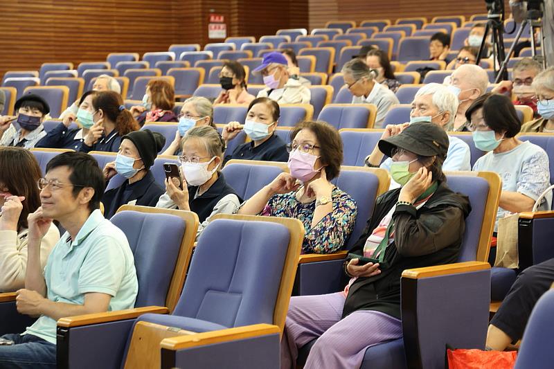 現場民眾聽著醫師講解，跟著按壓耳垂後位於頸部的翳風穴。