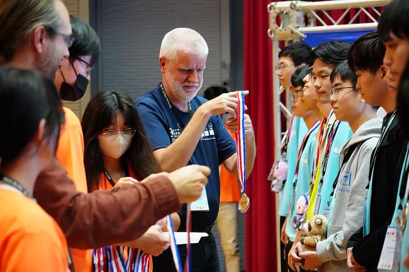 法國波爾多大學教授Dr. Ralf Klasing（中）頒發金獎給冠軍的新加坡國立大學隊。