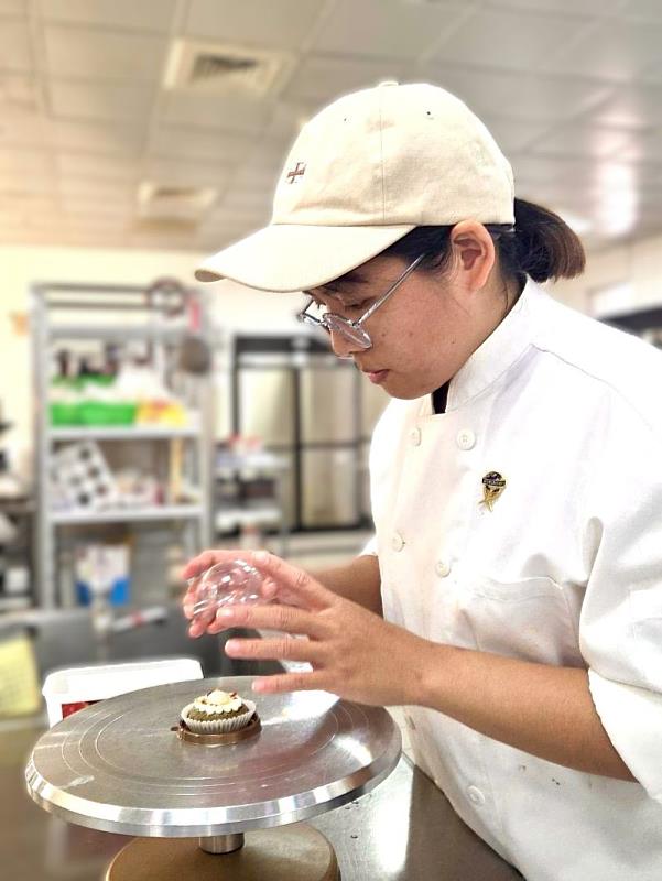 南臺科大餐旅系李依蓉同學在教室練習伴手禮盒作品的情景。李同學的作品以日系細膩美學為主軸，透過日常的專業訓練與自律管理，將實作技巧磨練至最佳狀態，最終榮獲金牌獎項，實至名歸。