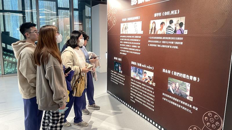 高中生在展牆前討論作品內容，展現主動學習與文化思辨力。