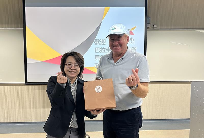 臺南市沙崙人工智慧產業專區管理辦公室楊亭鈺執行秘書贈禮給巴拉圭伊泰布省貝雷拉省長。（圖/臺南市經濟發展局提供）
