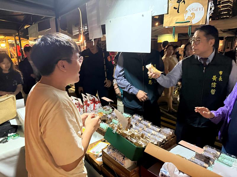 台南市長黃偉哲（右）親臨公廣系畢製攤位，團隊成員陳柏翰（左）親自介紹品牌理念與商品特色。