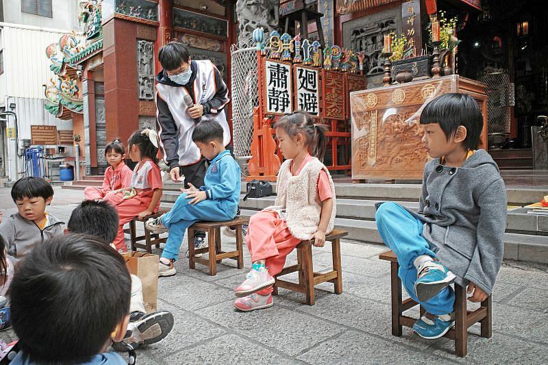 幼童透過模仿廣澤尊王翹腳端坐的典型姿態，在趣味互動中加深對神明形象的記憶，讓信仰文化更貼近生活。
