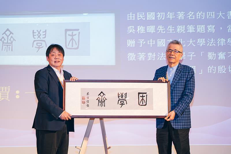 信義企業集團創辦人周俊吉校友(右)成功拍得「困學齋」畫作,以行動支持母系發展。左為王子奇校長。