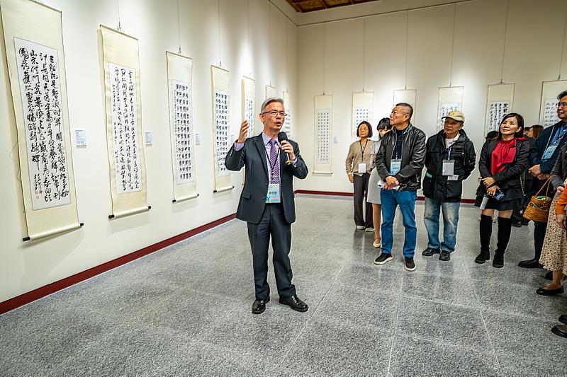 著名書法家楊旭堂為現場賓客導覽藝文比賽得獎參展作品，賞析書法藝術之美。