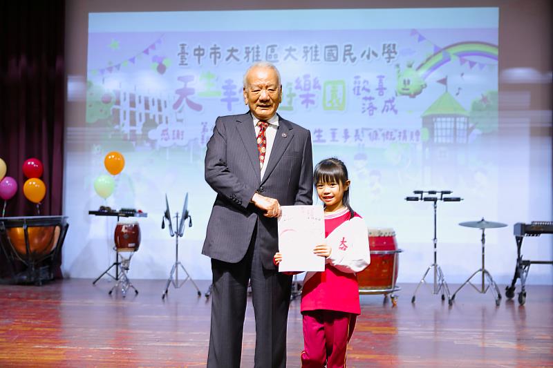 大雅國小學童代表送上感恩卡，謝謝楊天生爺爺（左）送他們一座遊樂園。