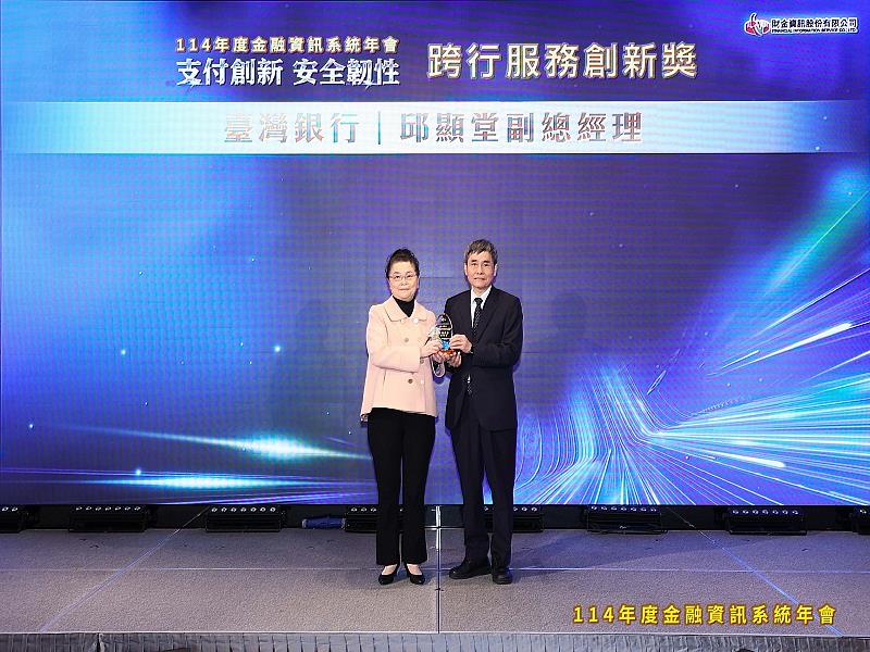 114年12月4日臺灣銀行於金融資訊系統年會榮獲「跨行服務創新獎」肯定，由中央銀行業務局局長謝鳳瑛（左）頒獎，臺灣銀行副總經理邱顯堂（右）出席領獎。